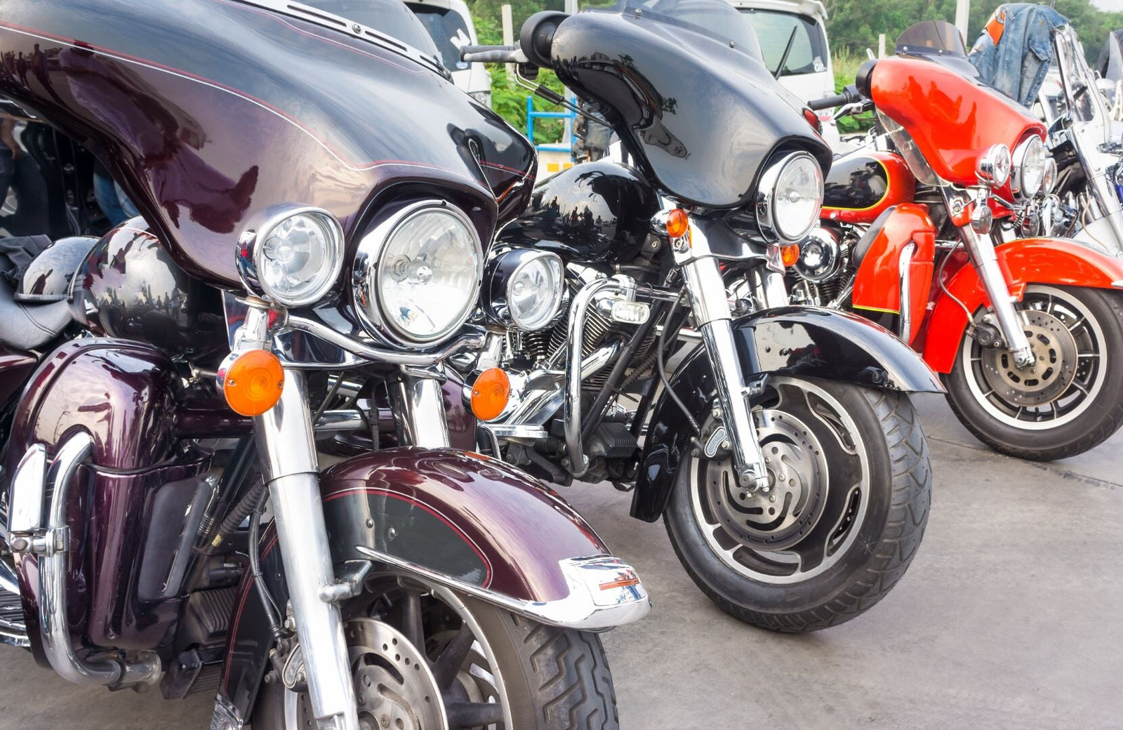 A line of motorcycles of the same make and model in colors such as maroon, black, and red. They all face the same direction.