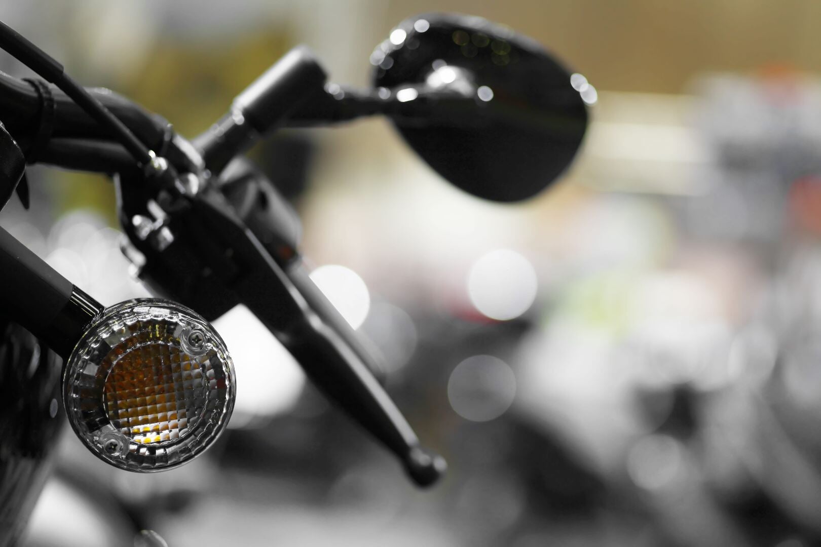 A close-up of a motorcycle's left handlebar with a focus on the circular turn signal light that has no illumination.