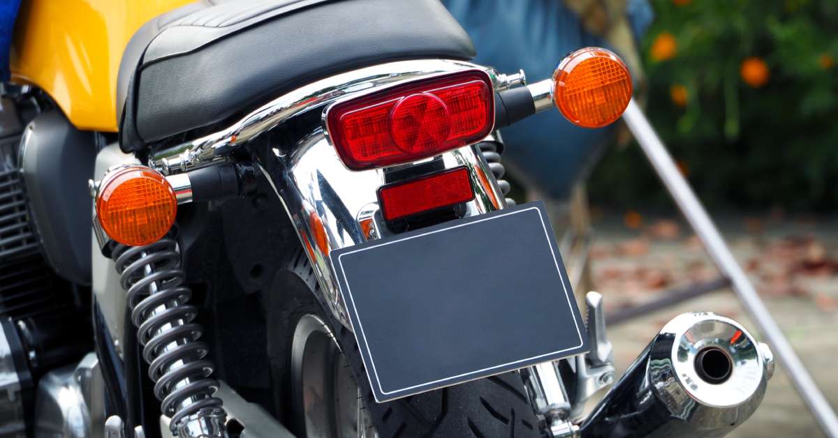 Two orange taillights and one red brake light on a black and yellow motorcycle. The motorcycle is parked.