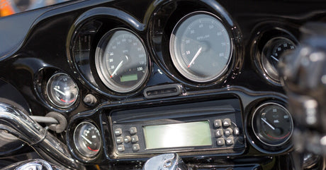 A motorcycle dashboard features a radio interface, an RPM gauge, a fuel gauge, a speedometer, and an oil pressure gauge.